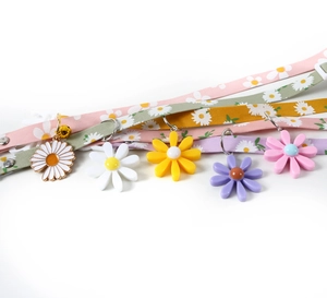 Detail of adjustable pet collars with daisy charms and bells in multiple pastel colors