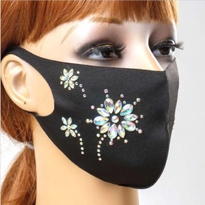 Detail of black fabric face mask with shimmering rhinestone floral and firework patterns
