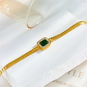 Elegant gold Cuban chain necklace with an emerald green square zircon pendant on marble