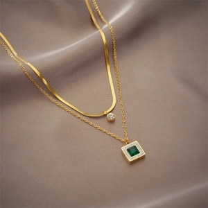 Gold double-layer necklace featuring a flat snake chain and emerald green square pendant
