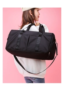 Side view of black nylon fitness bag with shoulder straps over pink background