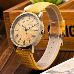 Vista macro di un orologio retrò in tela gialla con cassa in bronzo su superficie in legno