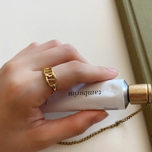 Close-up of a gold link chain ring worn on finger with minimalist aesthetic props