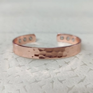 Detailed close-up of rose gold magnetic copper bracelet with hammered texture finish