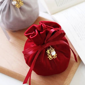 Red velvet wedding candy bag with gold Xi character and pearl charm on wooden tray