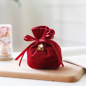 Detailed view of red velvet wedding candy bag with gold double joy charm and pearl