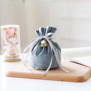 Detail of grey velvet wedding favor bag with gold Xi character charm and pearl