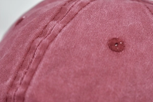 Macro shot of burgundy washed cotton ponytail hat with reinforced stitching and eyelet