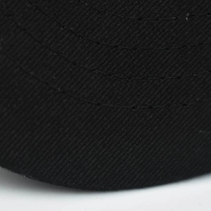 Macro shot of high-density black twill fabric with parallel curved stitching on cap brim