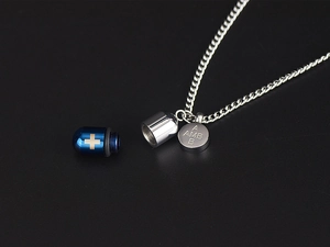 Detalle del colgante de cápsula abrible en acero inoxidable azul y plata con una cruz