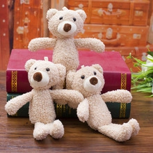 Three small beige plush bears displayed on vintage luggage with soft lighting