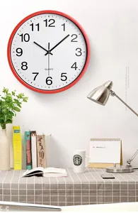 Close-up of red silent quartz wall clock with white dial and black Arabic numerals