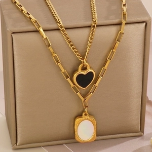 Detail of layered gold necklace with heart pendant and shell inlay on jewelry box