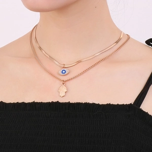 Close-up of double layer gold necklace with blue evil eye and hamsa hand pendants