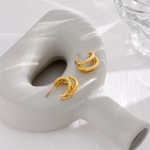 Three-layered gold titanium steel hoop earrings on minimalist ceramic pedestal