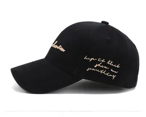Side view of a black cotton baseball cap with intricate gold script embroidery and curved brim