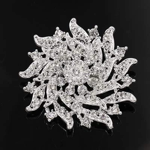 Macro detail of silver floral brooch featuring layered petals and sparkling rhinestones