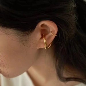 Macro view of matte gold irregular curved ear cuffs worn as a stylish two-piece set