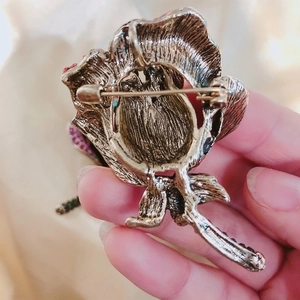 Vintage bronze rose brooch with purple rhinestones showing secure back pin clasp
