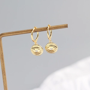 Macro detail of S925 sterling silver hoop earrings featuring engraved evil eye pendants