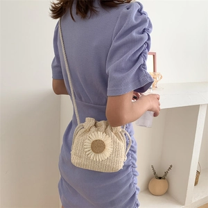 Detail of woven straw bucket bag with large white sunflower decor and drawstring closure