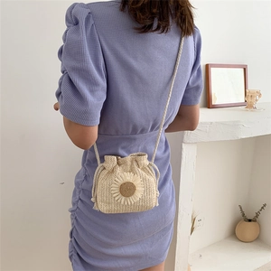 Detail of hand-woven straw bucket bag with sunflower accent on purple dress model