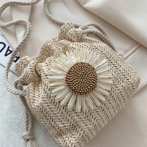 Handmade straw bucket bag with large white daisy decoration and drawstring closure