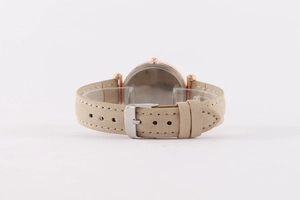 Detail of rose gold watch case back with beige matte faux leather strap and buckle