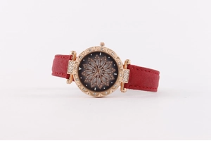 Detailed macro of rose gold bezel with rhinestones and 3D floral dial on red strap