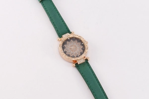Detailed macro view of an emerald green leather strap and rose gold floral carved dial