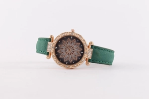 Detail of rose gold quartz watch featuring a green leather strap and floral diamond dial
