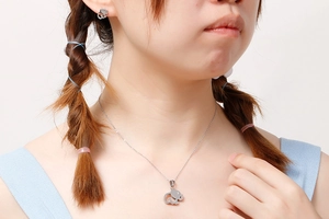 Close-up of silver elephant jewelry set including necklace and earrings worn by a model