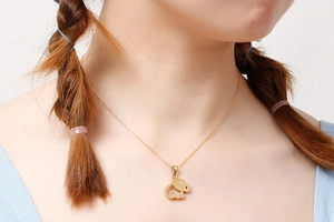 Close-up of gold elephant necklace with sparkling stone on a model's neck