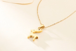 Dettaglio di un'elegante collana dorata con un ciondolo minimalista a forma di renna