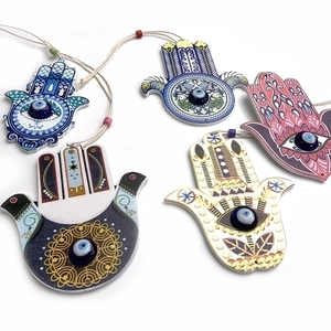 Close-up of colorful wooden Hamsa hand wall hangings with classic blue Evil Eye beads