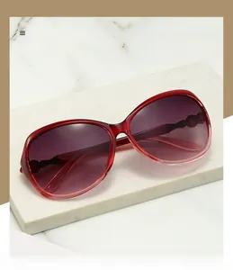 Detailed macro view of burgundy oval sunglasses with polarized gradient lenses on marble