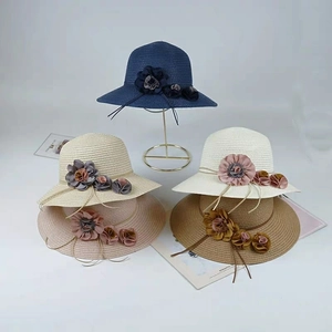Detail of colorful straw sun hats with floral decor on a golden display stand