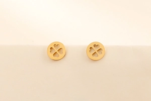 Gros plan de boucles d'oreilles rondes dorées avec motif trèfle à quatre feuilles ajouré