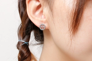 Gros plan d'un mannequin portant des boucles d'oreilles trèfle à quatre feuilles en argent