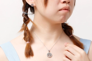 Silver hollow Tree of Life necklace and earrings set worn by a female model