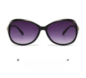 Close-up of black oval frame sunglasses with purple gradient lenses and gold metal hinges