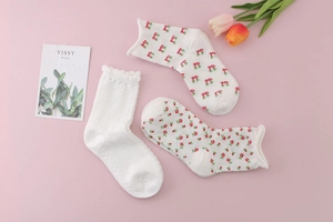 Detail of floral and cherry pattern socks with ruffled cuffs on pink background