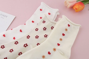 Detail of three mid-calf cotton socks with heart patterns and elegant ruffled edges