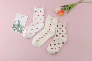 Detailed close-up of three pairs of cotton socks with red heart and flower patterns