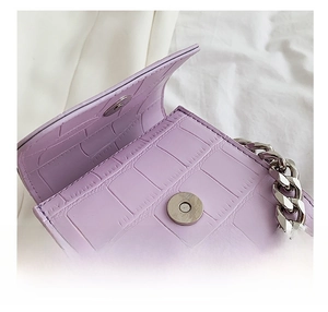 Close-up of lavender crocodile pattern handbag with silver magnetic buckle and chain strap