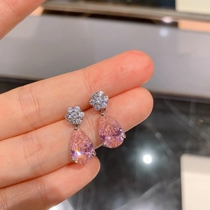 Elegant pink pear-cut gemstone drop earrings with floral zircon accents held by hand