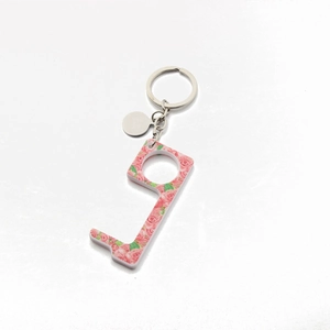 Macro detail of acrylic door opener with pink rose floral pattern and metal keyring
