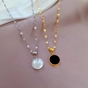 Double-sided shell pendant necklaces in gold and silver steel on a soft fabric background