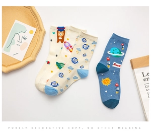 Flat lay of cotton mid-tube socks featuring rocket, bear, and planet space patterns