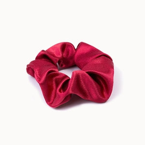 Detailed close-up of dark red satin scrunchie showing glossy texture and silk folds